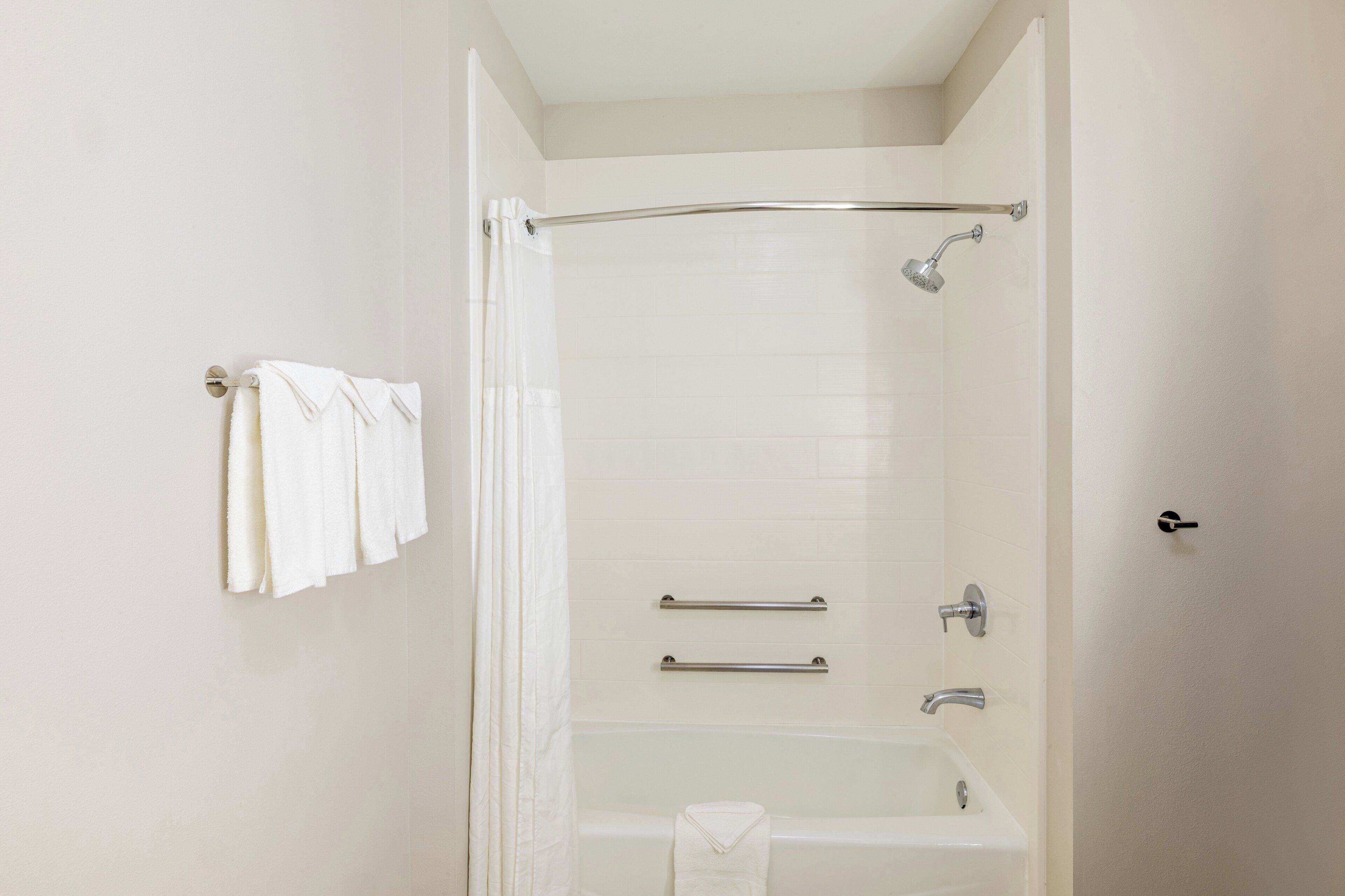 A bathroom with a bathtub, a shower, and a towel rack with towels.