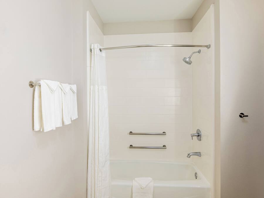 A bathroom with a bathtub, a shower, and a towel rack with towels.
