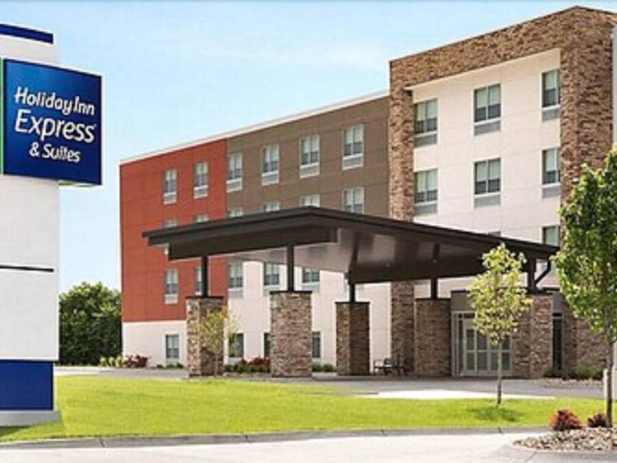 Un hôtel Holiday Inn Express & Suites doté d’un bâtiment moderne, d’une entrée abritée et d’une pelouse bien entretenue.