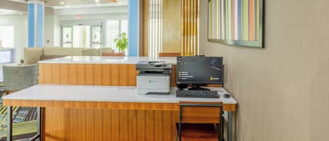 A reception desk with a printer, computer, and seating area.