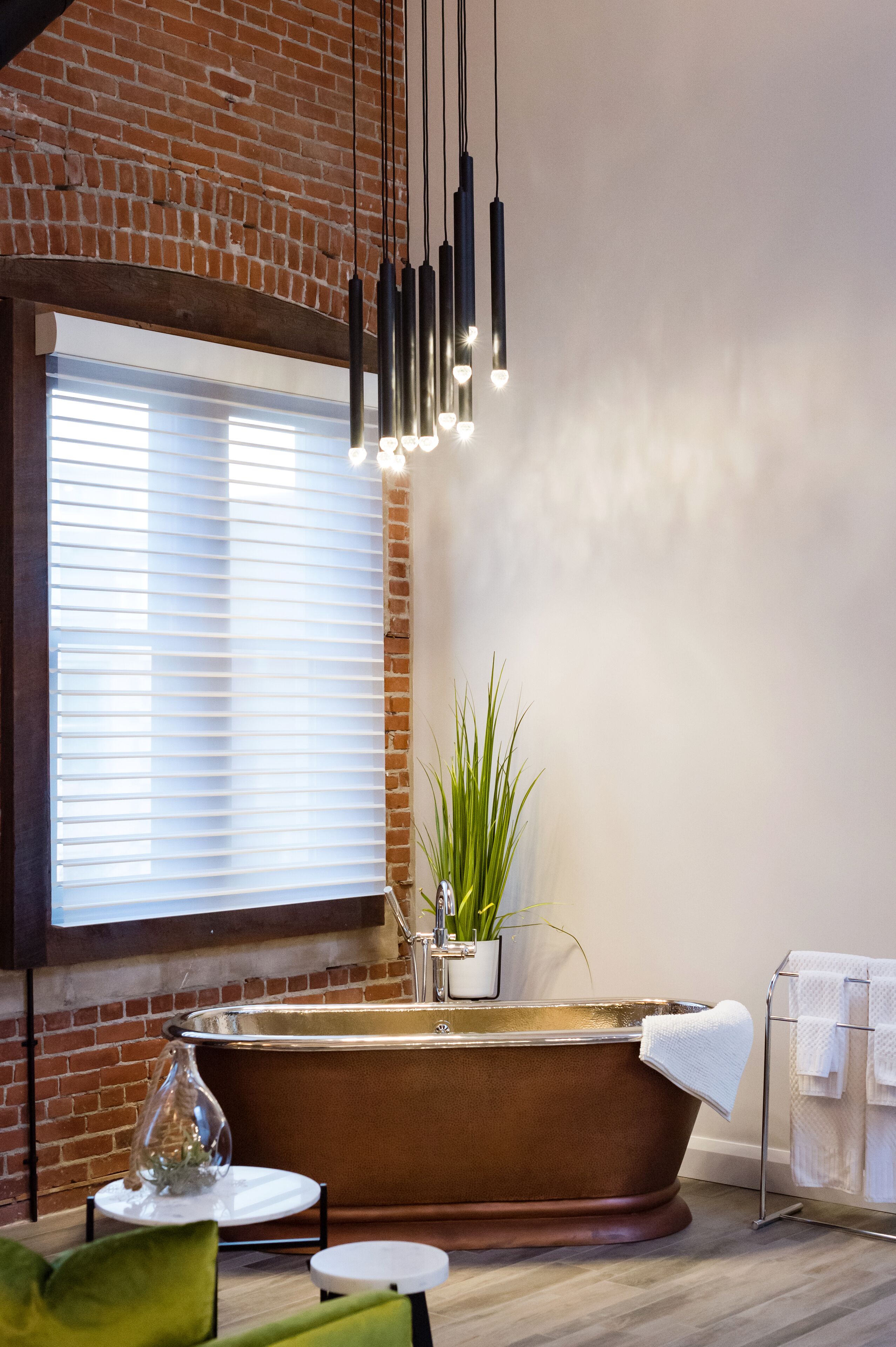 Un baño moderno con una bañera grande, una planta en maceta y un perchero para toallas.