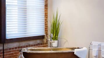 Un baño moderno con una bañera grande, una planta en maceta y un perchero para toallas.