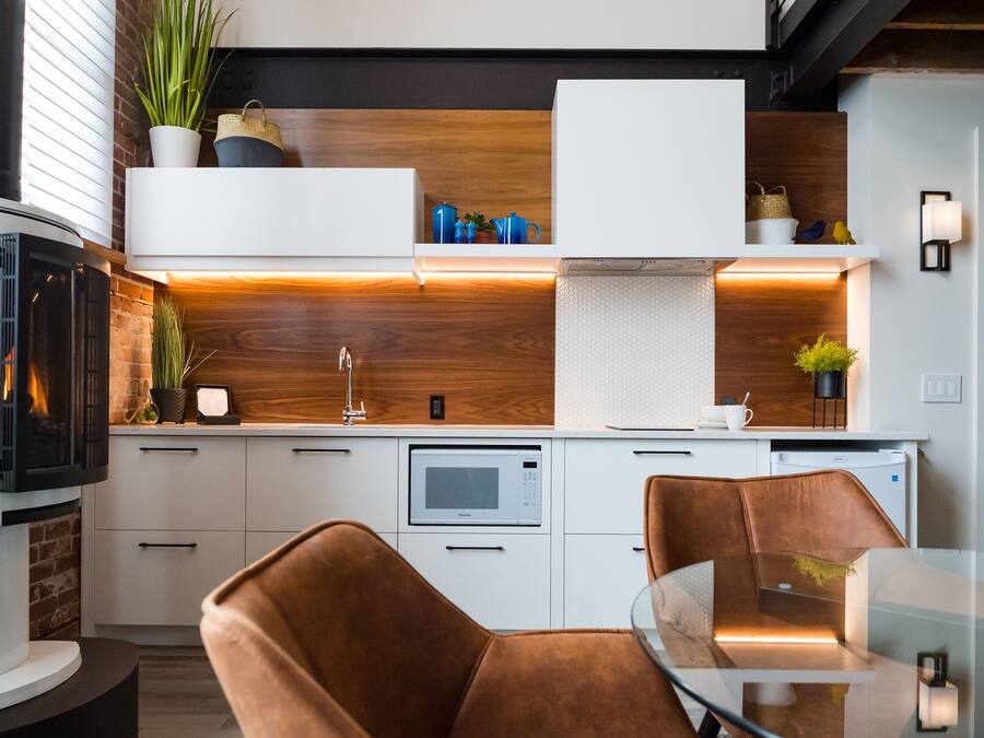 A modern kitchen with a built-in stove, white cabinets, and a glass dining table.