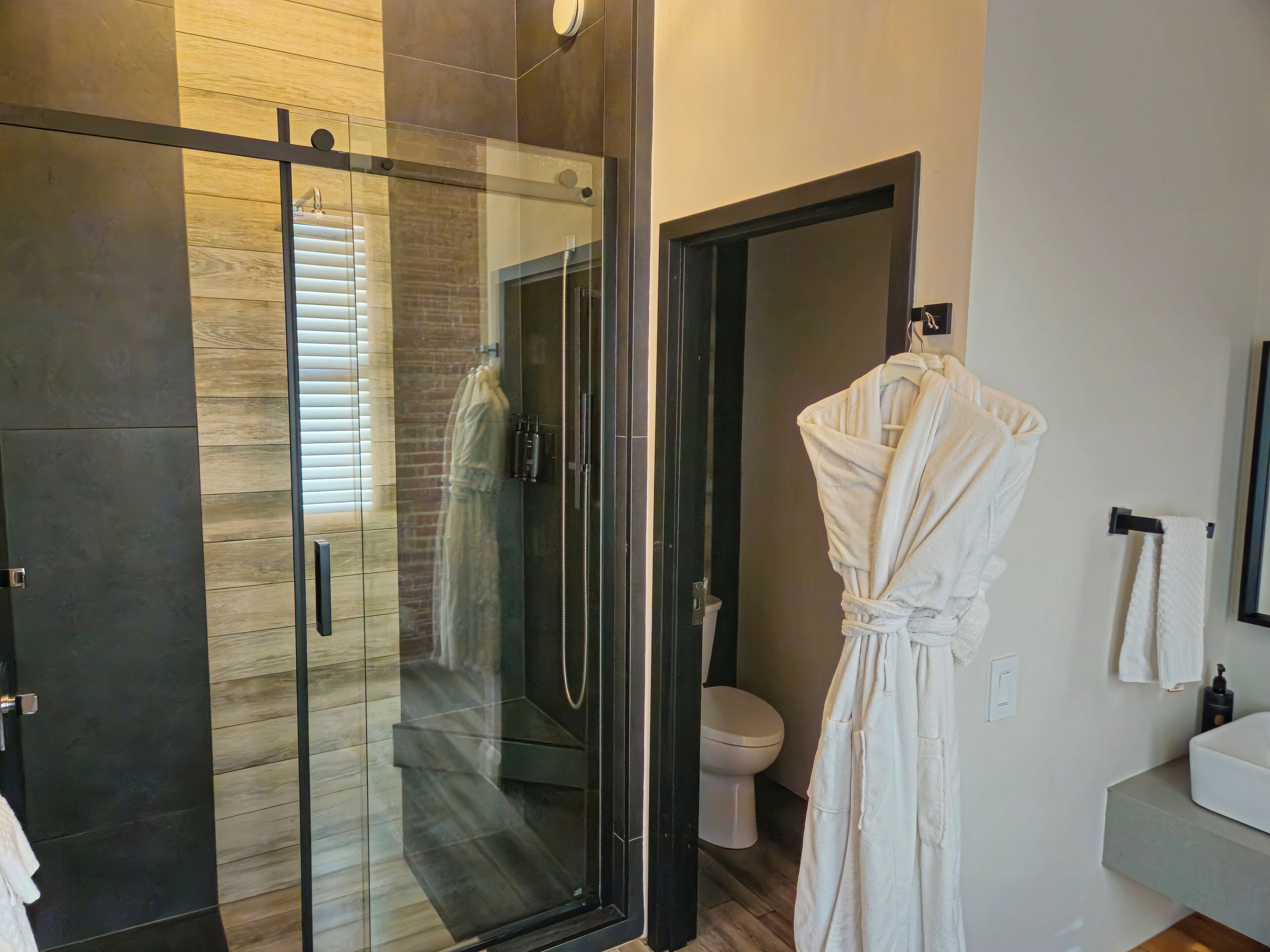Un baño moderno con ducha acristalada, bañera blanca y retrete.