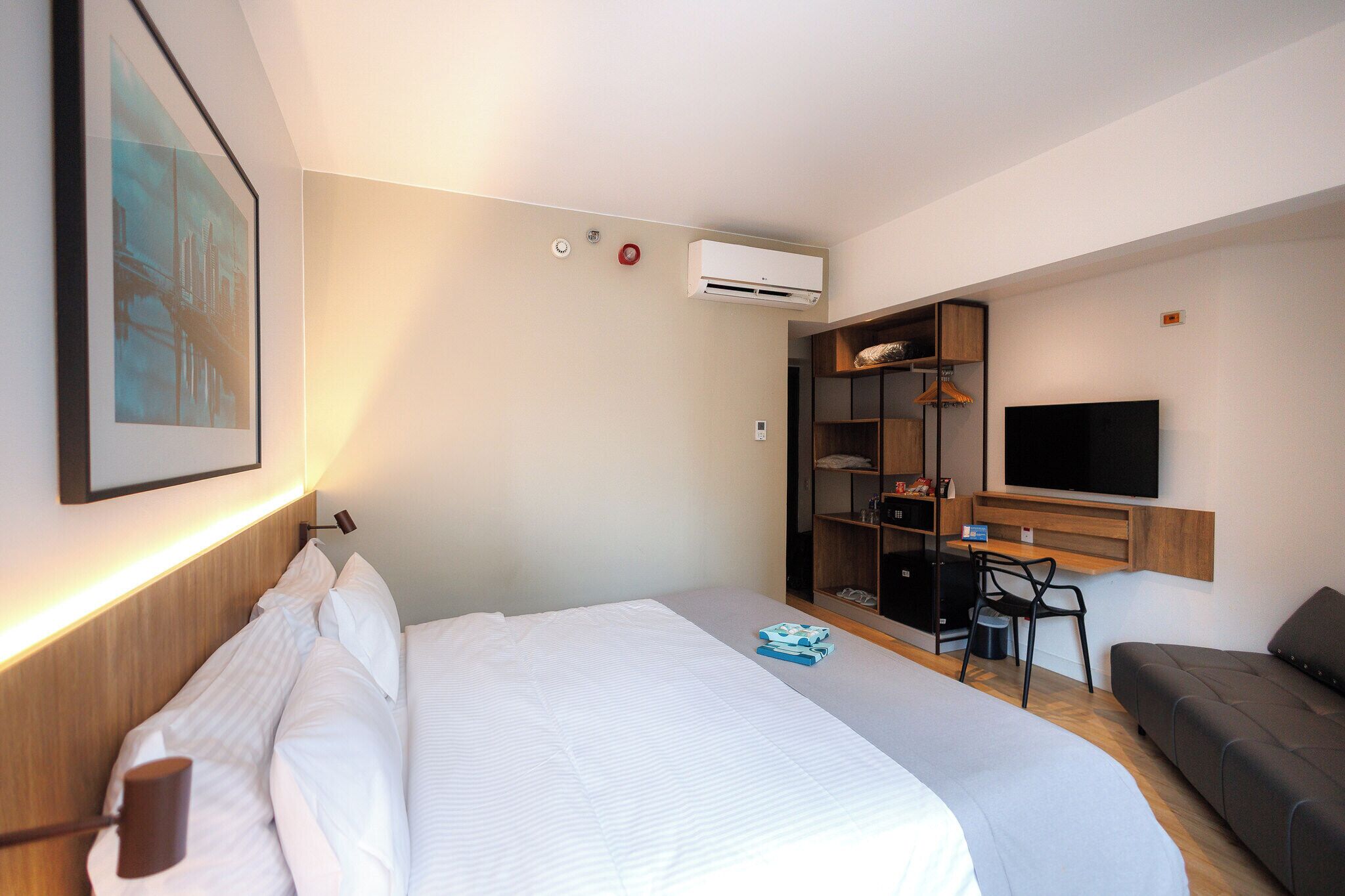 A hotel room with a bed, a desk, a TV, and a wardrobe.