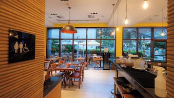A restaurant interior with wooden paneling, large windows, and hanging pendant lights.
