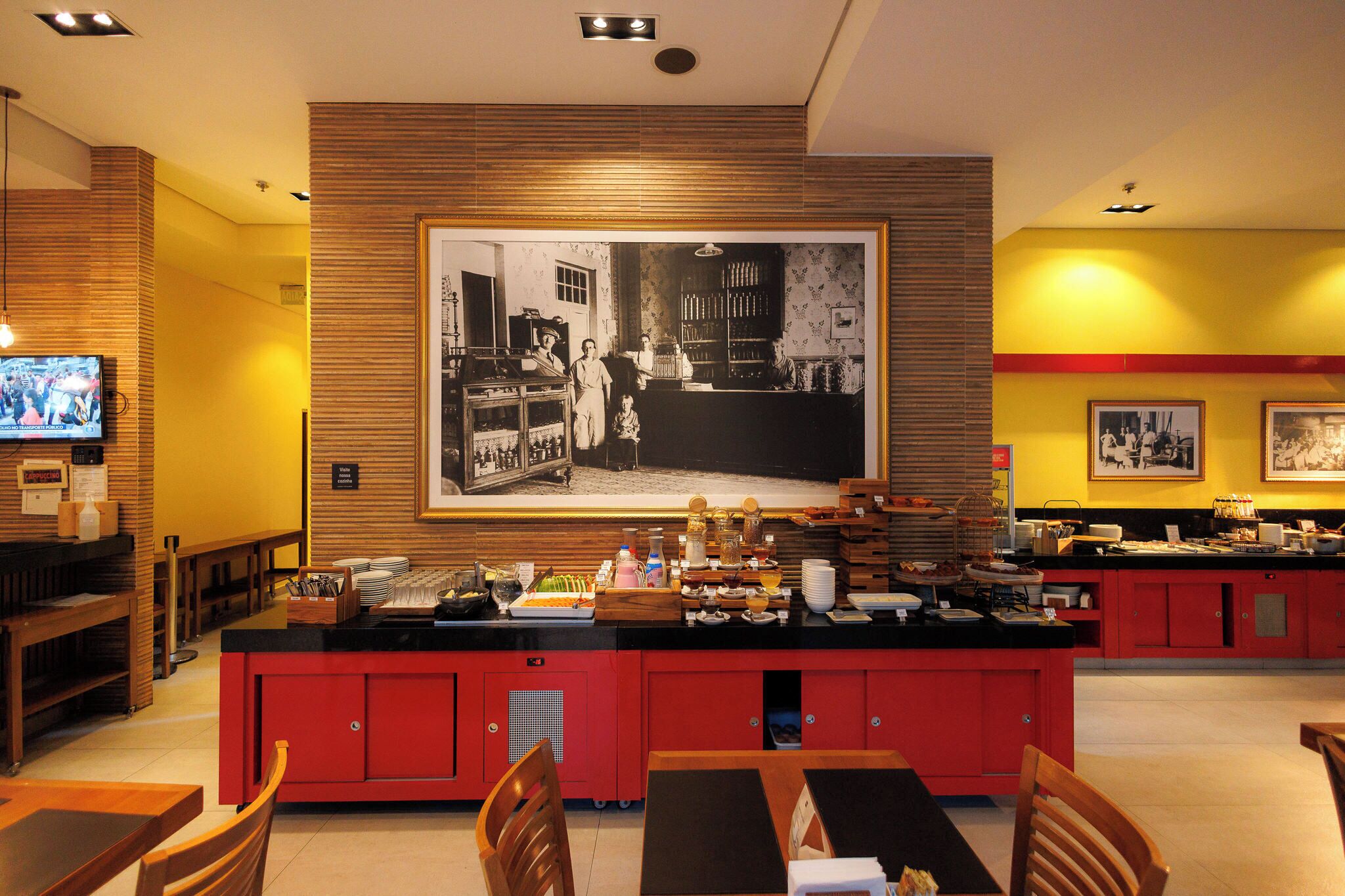 A restaurant with a counter, chairs, and a television.