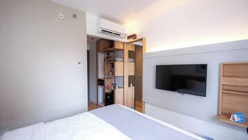 A bedroom with a bed, a TV mounted on the wall, and a wooden wardrobe.