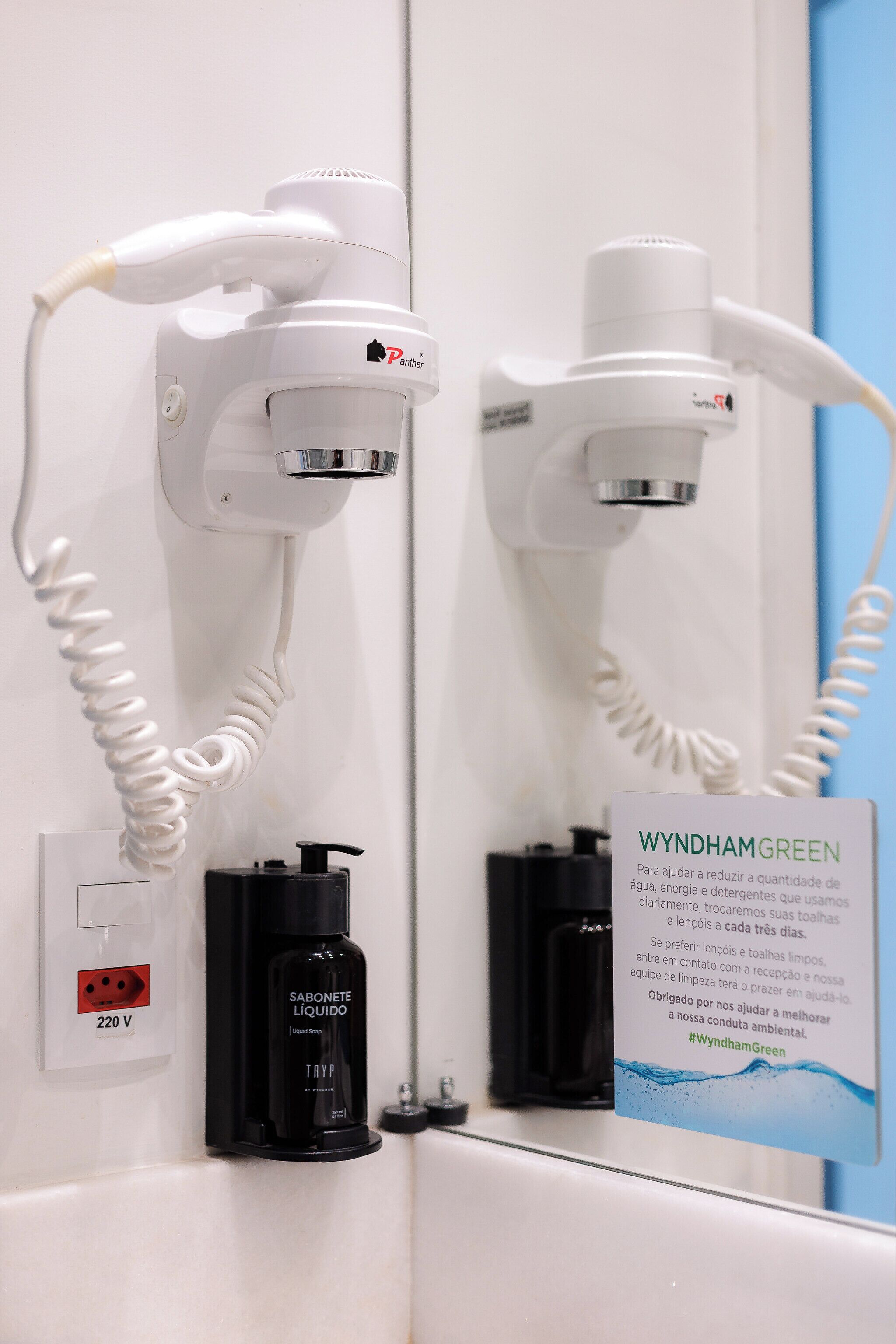A bathroom with a hairdryer and a soap dispenser mounted on the wall.