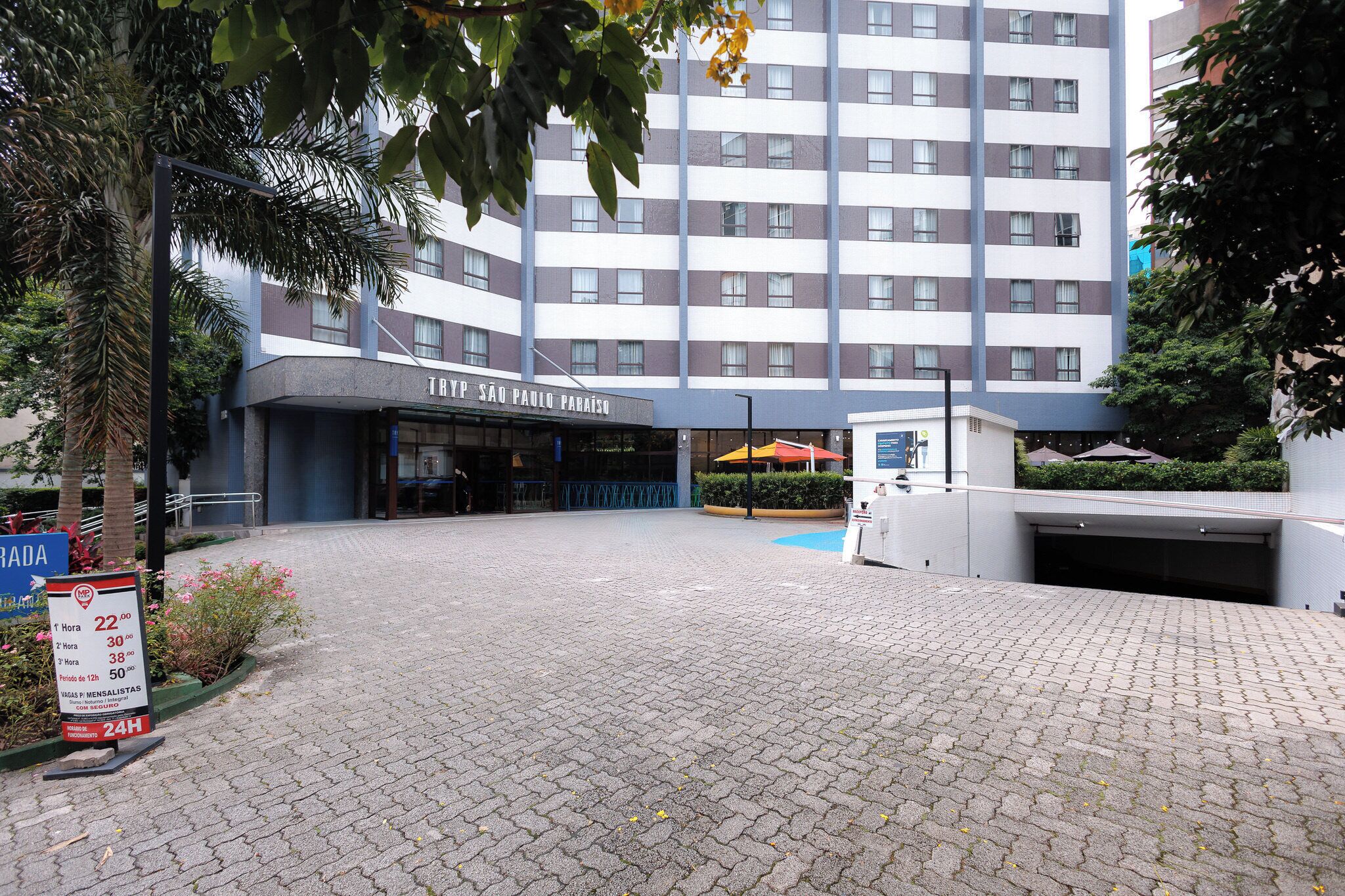 Entrada de hotel con un cartel que dice 'TRYP SAO PAULO PARAISO', suelo pavimentado y una zona de estacionamiento.