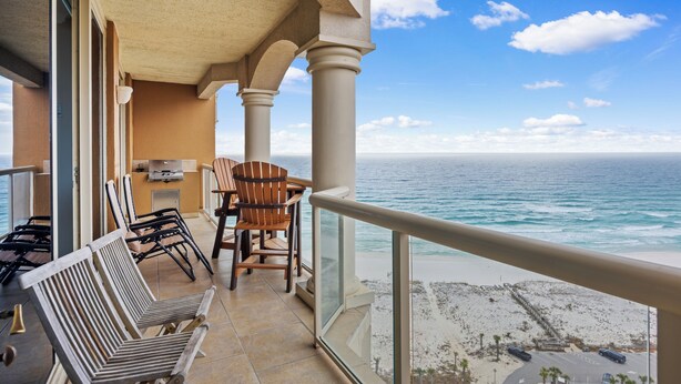 A balcony with a view of the ocean, wooden chairs, and a table. - Amazing Gulf Views! - Tower 1 Unit 1803 (Pensacola Beach)