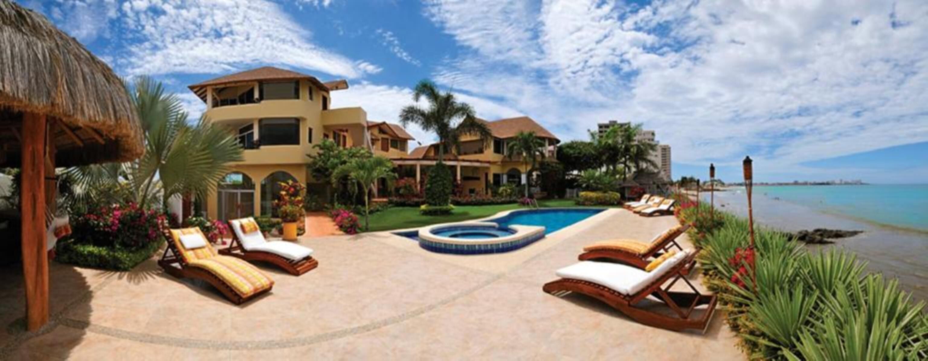A resort with a pool, lounge chairs, and a view of the ocean.
