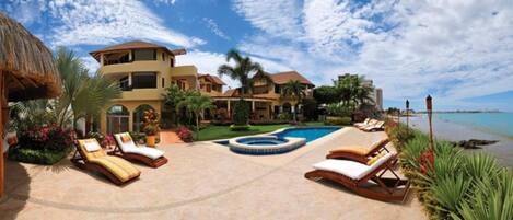 A resort with a pool, lounge chairs, and a view of the ocean.