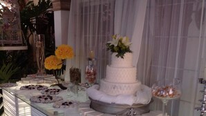 A buffet table with a tiered white cake, various desserts, and floral decorations.
