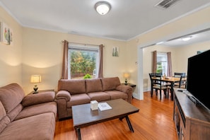 A living room with a sofa, a coffee table, and a dining area with a table and chairs.