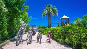 A paved pathway lined with bicycles and a playground structure. - Villa Euphoria (Rhodes)