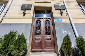 A hotel entrance with double doors, a sign above the door, and a number sign on the wall.