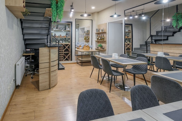 Un interior moderno con una escalera, comedor y estanterías llenas de botellas.