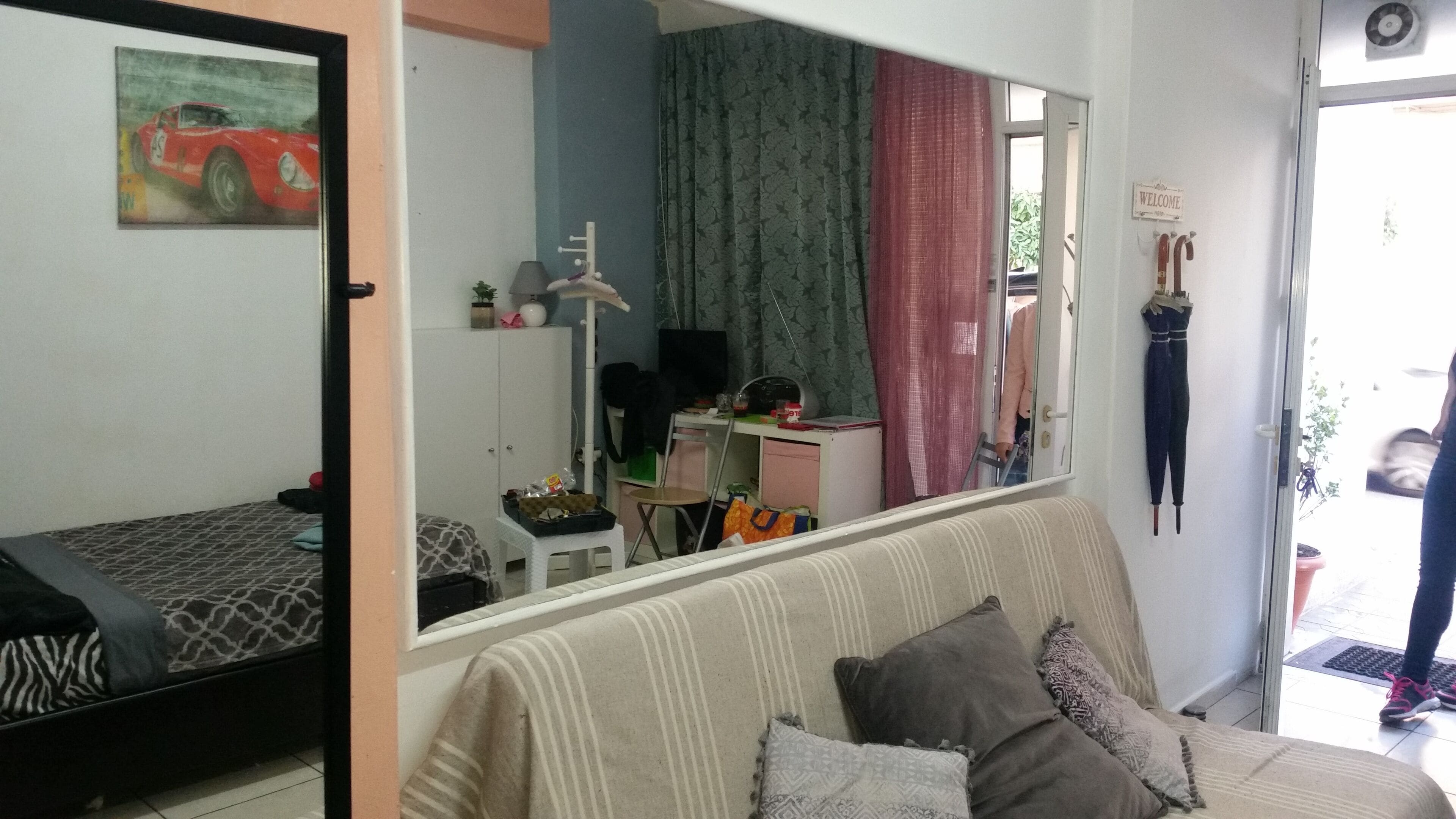 Una habitación con cama, escritorio, silla, espejo y ventana.