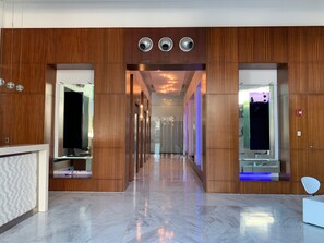 Un hall d'hotel modern amb panells de fusta, un paviment de marbre i una recepció.
