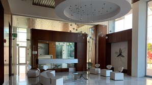 En moderne lobby med reception, siddeområde og et stort vindue, der giver naturligt lys.