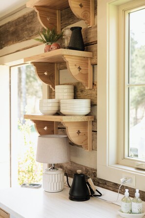 A kitchen with wooden shelves, a coffee maker, and a window with a view.