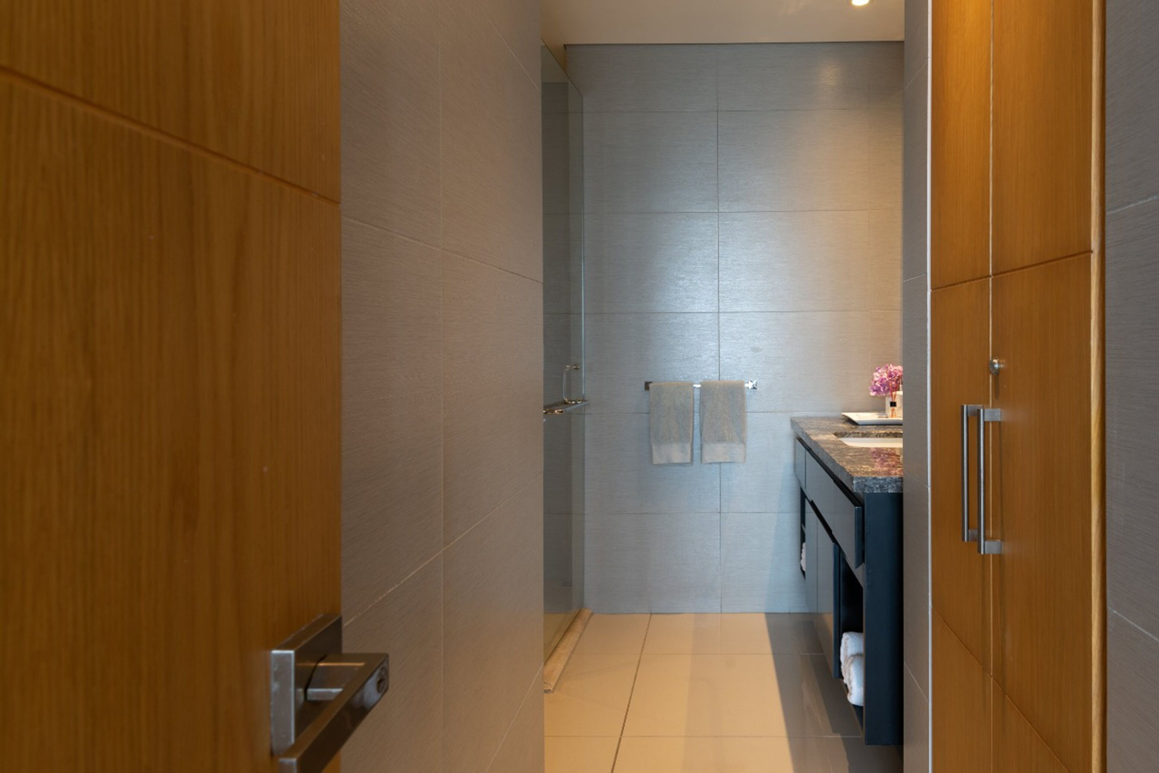 Une salle de bain moderne avec une douche, un lavabo avec un plan de travail et des meubles en bois.