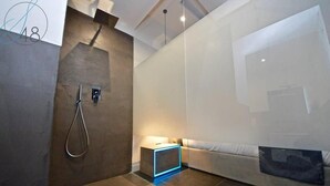 A modern bathroom with a shower, a small bedside table, and a sofa. - Suite Quarantotto Luxury House (Naples)