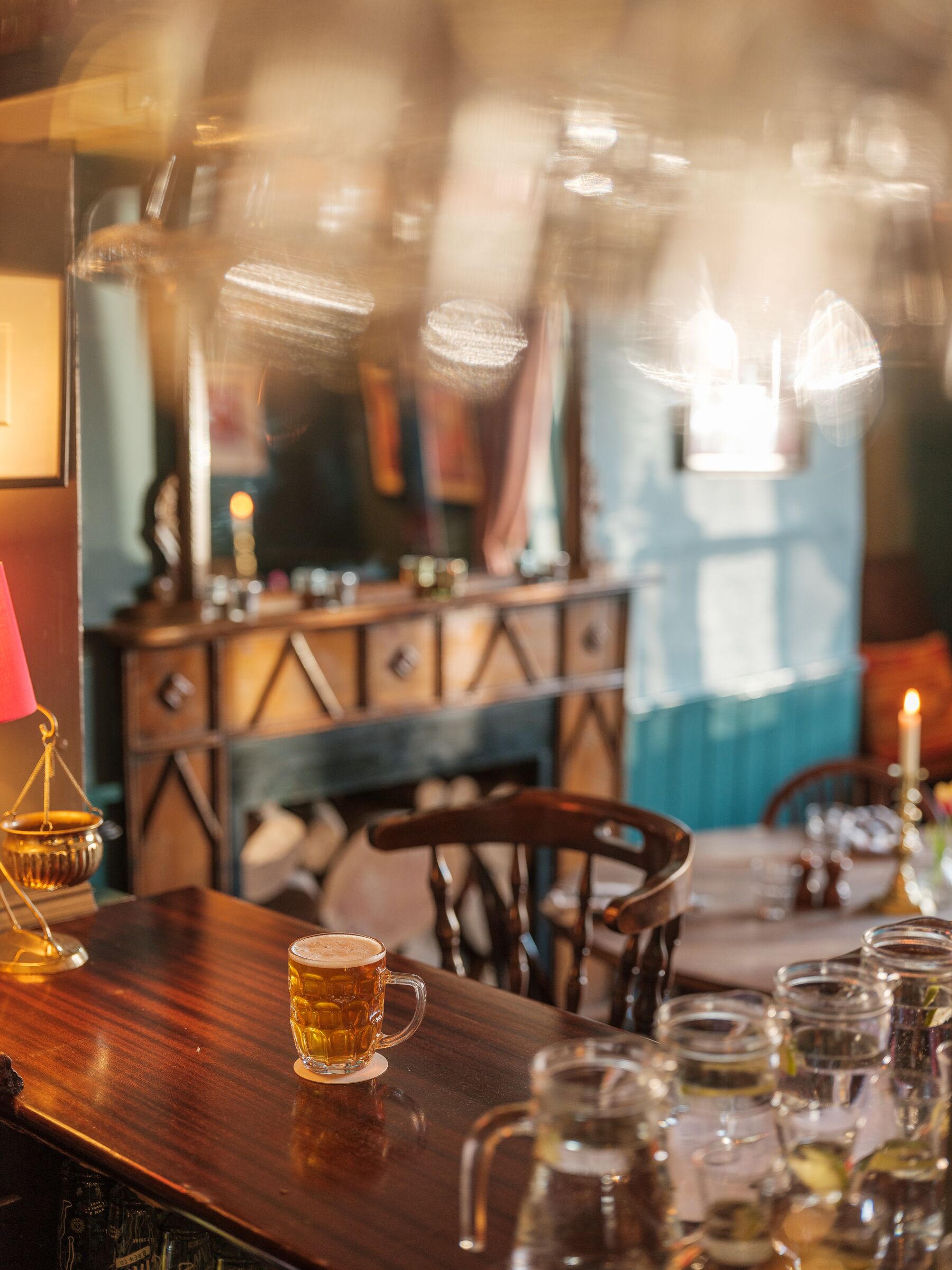 A bar area with a wooden table, a beer mug, and several glasses.