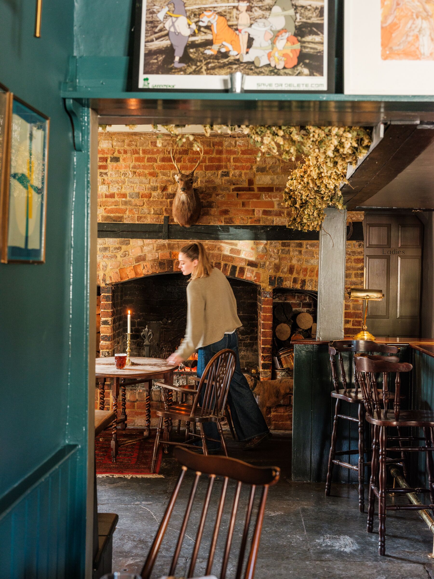 A cozy pub with a brick fireplace, wooden furniture, and a person serving.