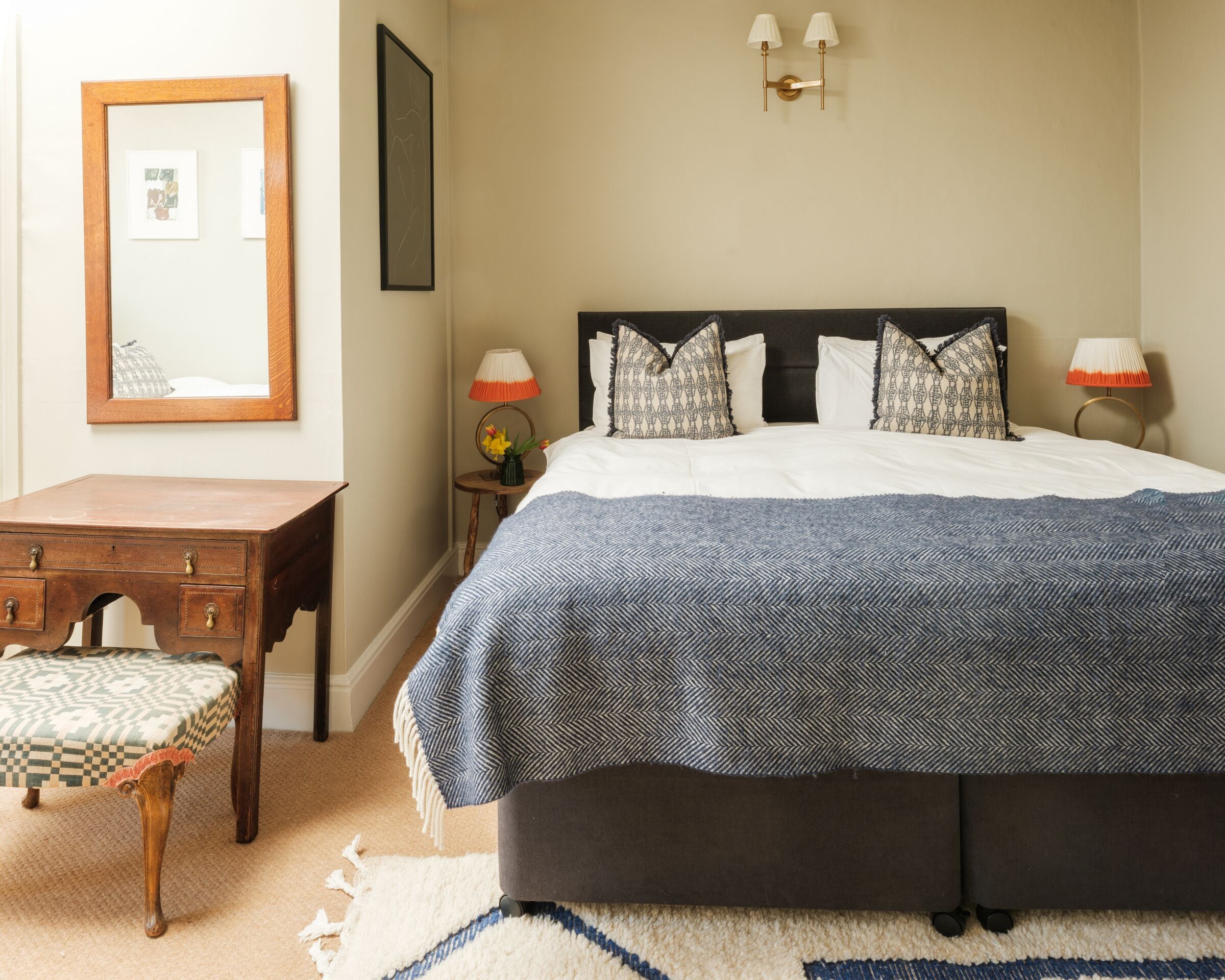 Un dormitorio con cama, mesita de noche, cómoda y espejo.