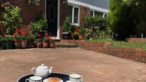A table with a teapot, two cups, and a plate of food on a brick patio. - Queens Road Rental - Winchester Accommodation (Winchester)
