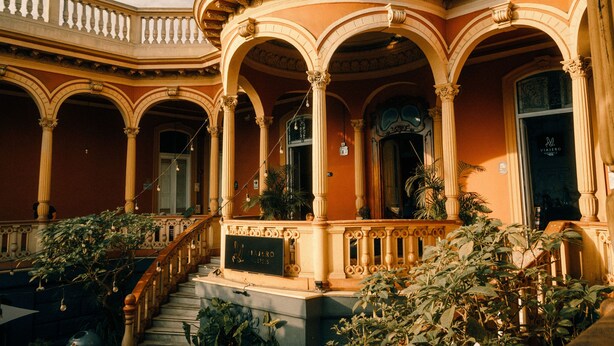 Un hotel con una entrada imponente, con columnas arqueadas y una escalera que conduce al edificio principal.