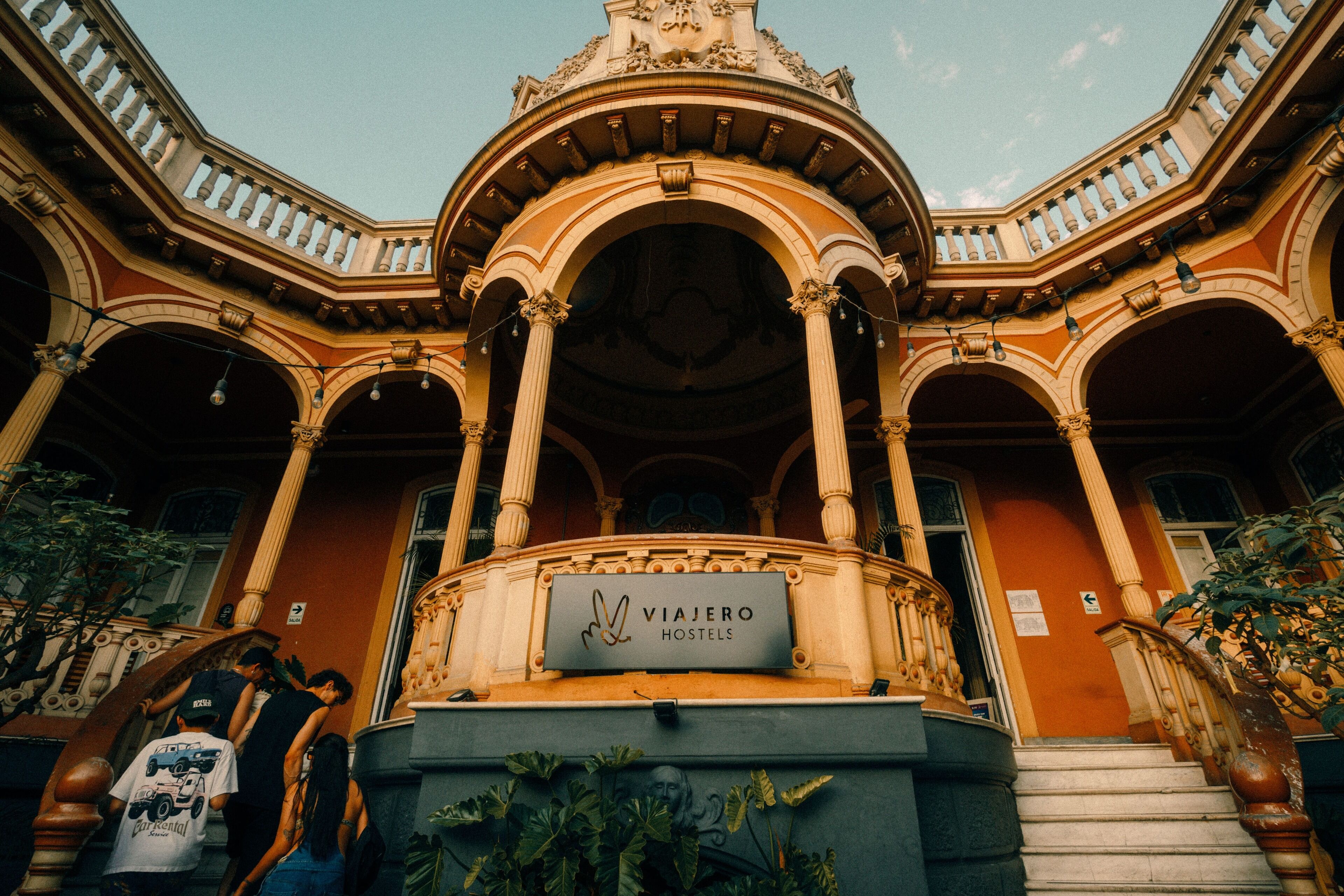 Un edificio con un arco central y columnas, con la inscripción 'Viajero Hostels'.