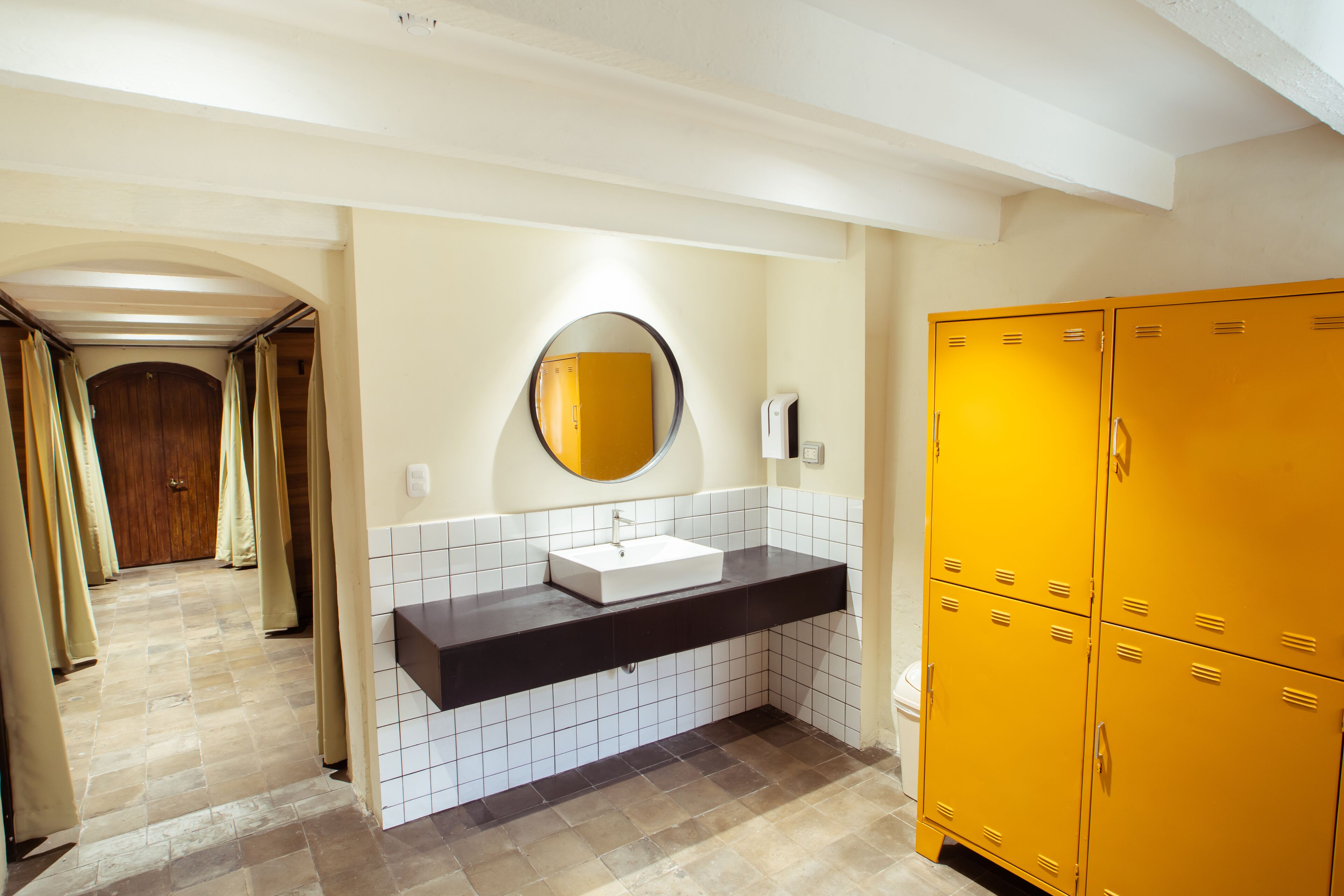 A bathroom with a white sink, a mirror, and yellow lockers.
