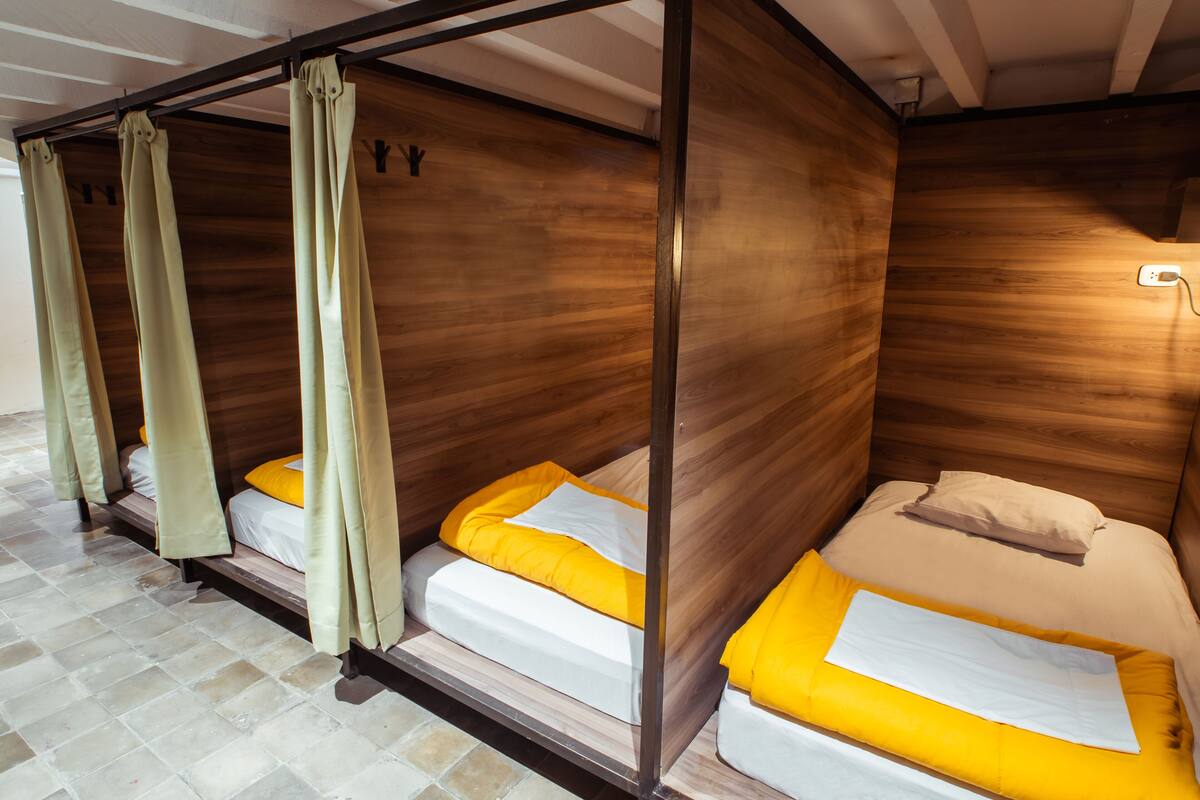 A room with three wooden bunk beds, each with a mattress and pillows.
