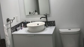 Et moderne badeværelse med en hvid vask, underskab og toilet.