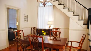A dining area with a wooden table and chairs, a chandelier, and a staircase.