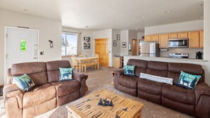 Ein großzügiges Wohnzimmer mit zwei braunen Ledersofas, einem Holztisch und einem Essbereich mit Holztisch und Stühlen.