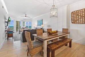 A spacious living area with a wooden dining table, wicker chairs, and a view of the ocean. - BEACHFRONT l PRIVATE BEACH l BEACH SET UP INCLUDED l STUNNING WATER VIEWS (Santa Rosa Beach)