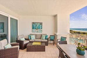 A balcony with wicker furniture, a sofa, and a table. - BEACHFRONT l PRIVATE BEACH l BEACH SET UP INCLUDED l STUNNING WATER VIEWS (Santa Rosa Beach)