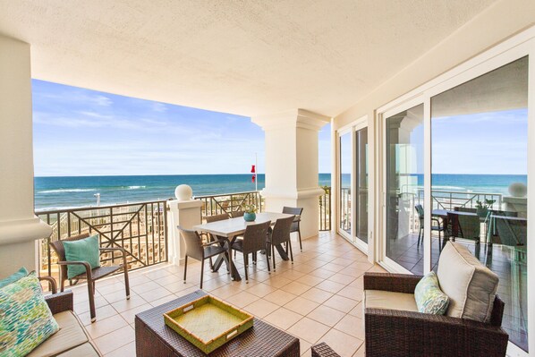 A balcony with a view of the ocean, furnished with wicker furniture and a dining table. - BEACHFRONT l PRIVATE BEACH l BEACH SET UP INCLUDED l STUNNING WATER VIEWS (Santa Rosa Beach)