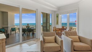 A spacious living area with a large sliding glass door leading to a balcony with a view of the ocean.