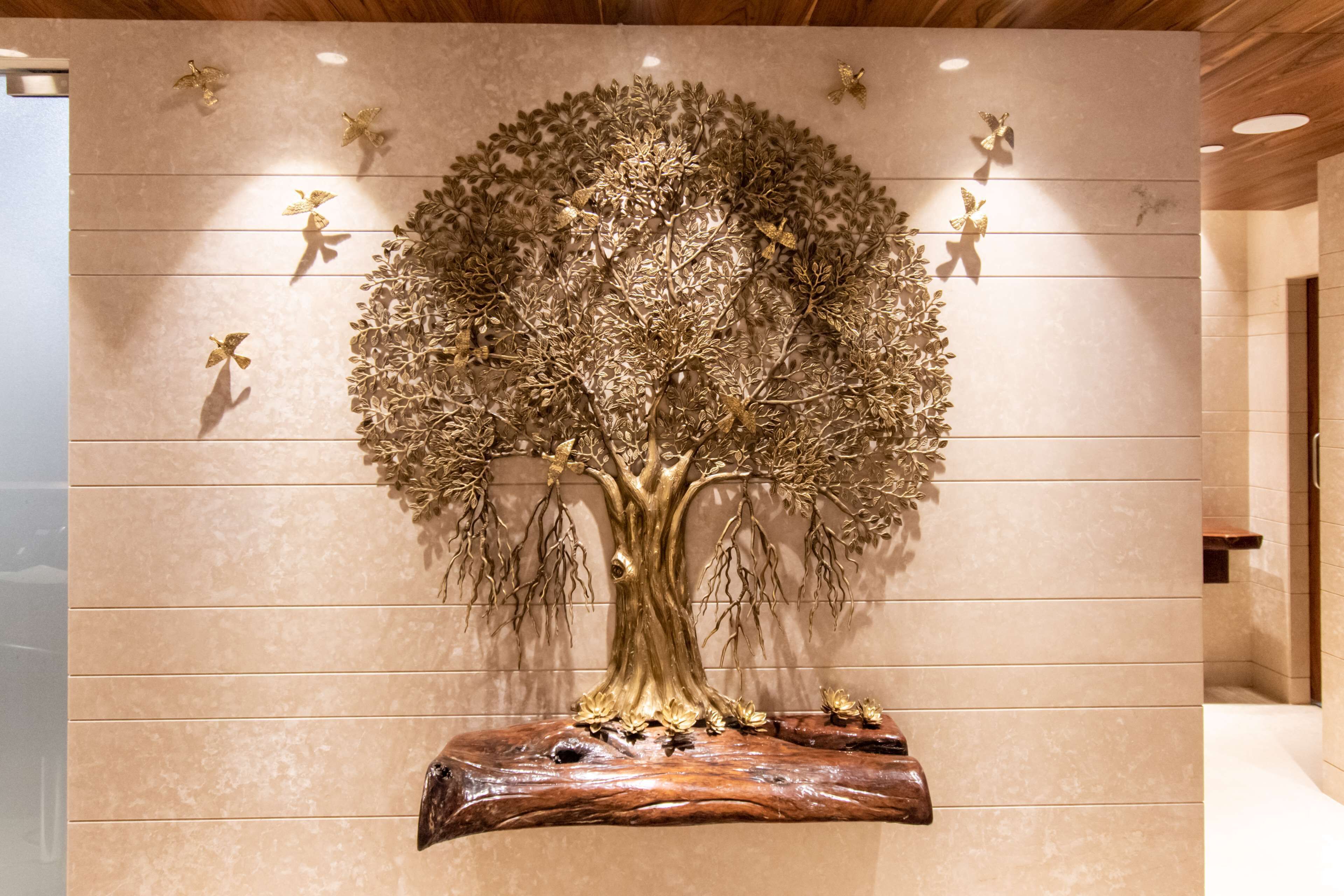 Scultura a forma di albero fissata al muro, con base in legno.
