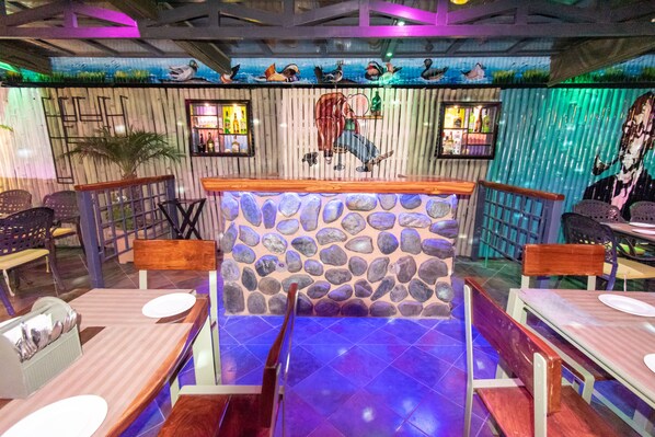 A restaurant with a stone wall backdrop, wooden tables, and chairs. - Best Western La Vista Pathankot (Pathankot)