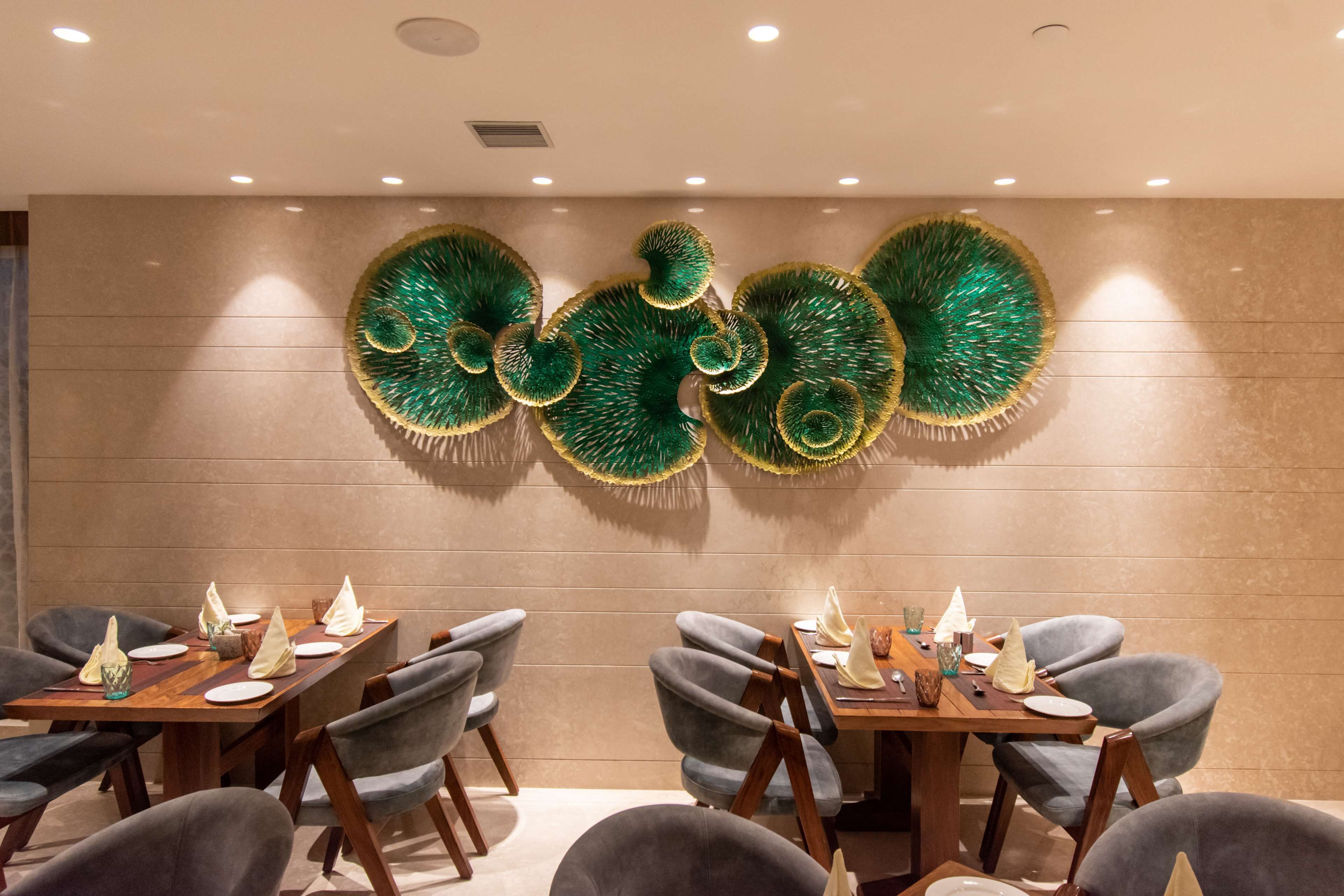 Un comedor con un interior moderno, que presenta una mesa larga con sillas, arte decorativo en la pared y una paleta de colores neutros.