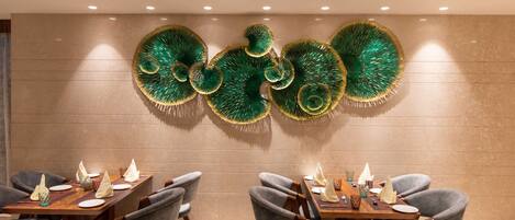 Un comedor con un interior moderno, que presenta una mesa larga con sillas, arte decorativo en la pared y una paleta de colores neutros.
