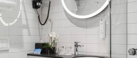 A modern bathroom with a round mirror, a sink, and a handheld hair dryer.