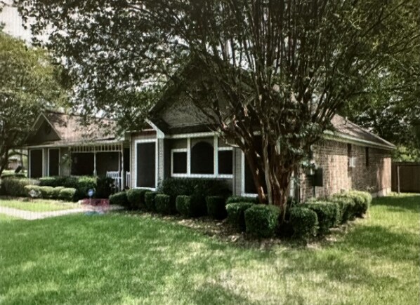Traditional home with a well-manicured lawn and a large tree in the front yard, featuring a pitched roof and a front porch.