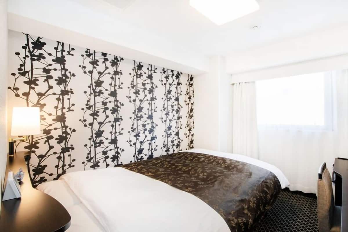 Une chambre d’hôtel avec un lit, un bureau, une télévision et une fenêtre avec des rideaux.